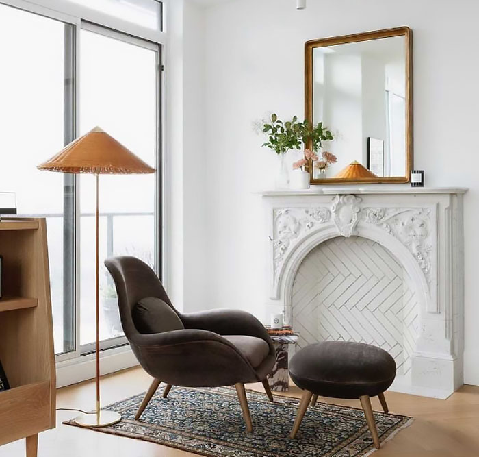 Ornate Victorian white arch fireplace mantel with floral carvings in a bright living room featuring modern furniture.