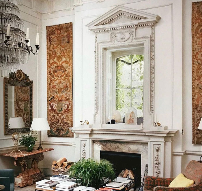 Stone fireplace mantel with decorative moldings and a window above in an elegant living room setting