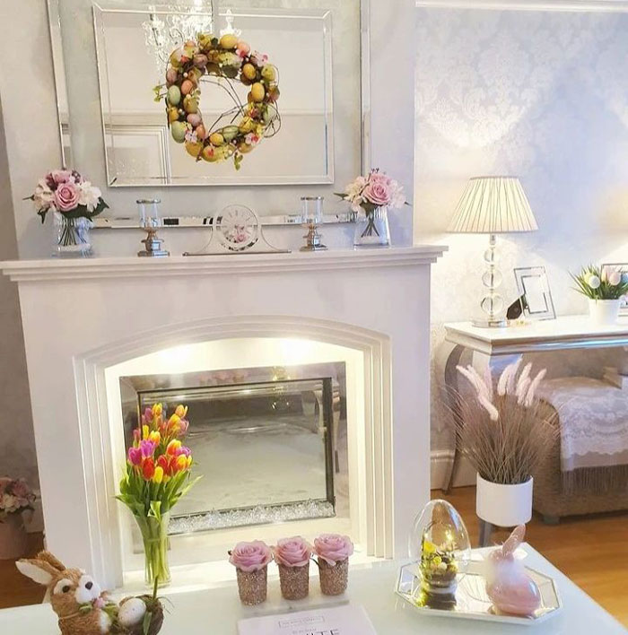 White fireplace mantel decorated with bright spring flowers and colorful wreath for cozy fireplace mantel ideas.