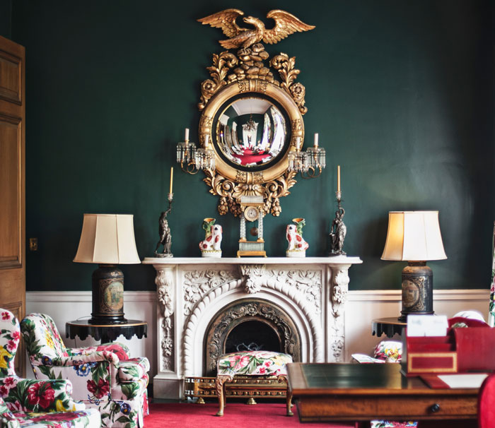 Intricately detailed fireplace mantel with ornate circular mirror and decorative accents in a classic elegant room setting