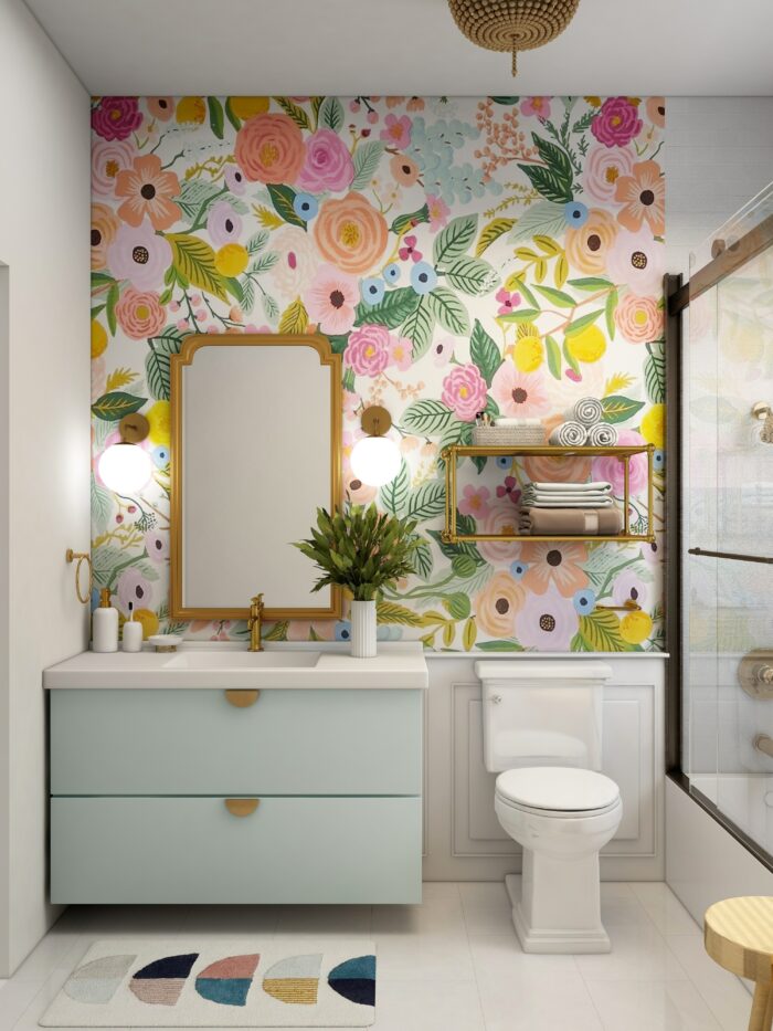 Bathroom featuring trendy flower wallpaper, a sink with blue cabinets, and a white toilet in a bright space.