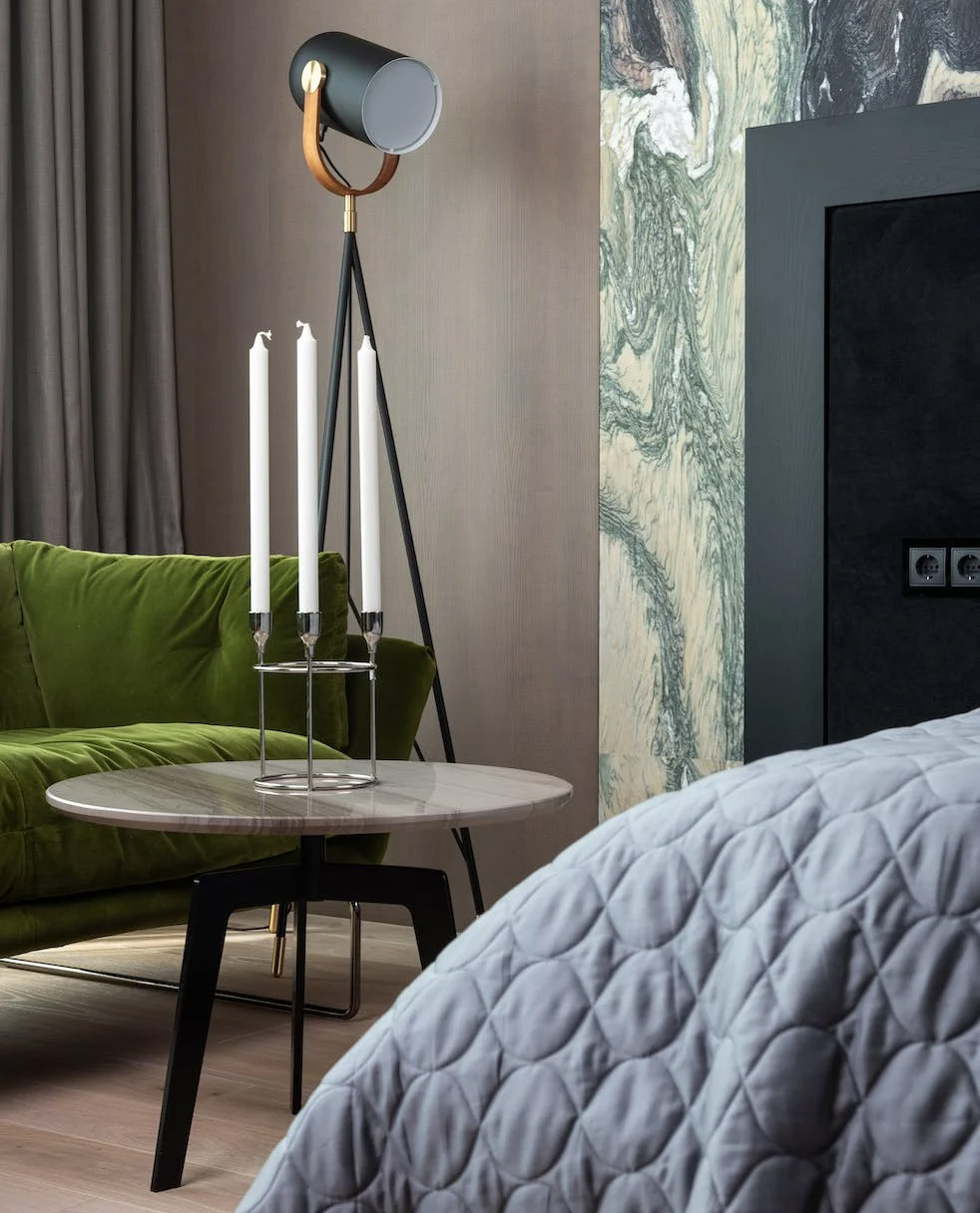 Round table with candlesticks near forest green sofa