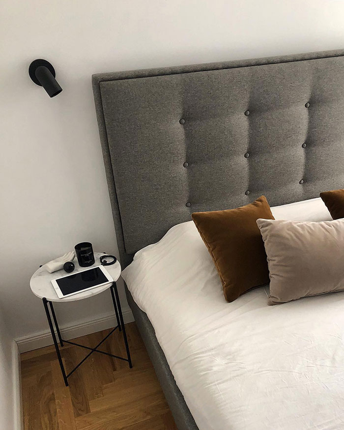 Colorful pillows arranged on a gray upholstered bed with a bedside table, showcasing stylish home decor ideas.