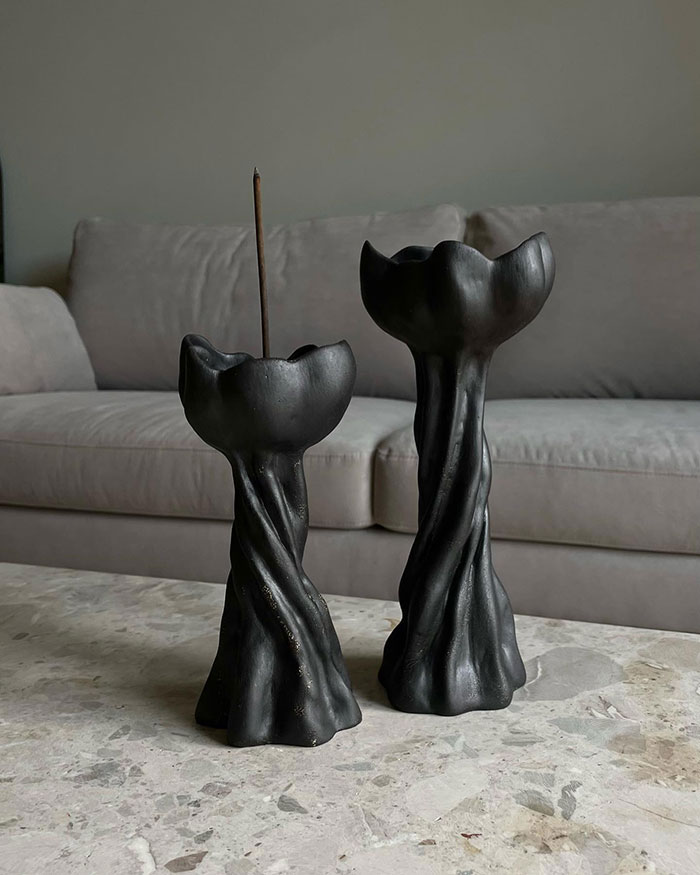 Two black sculptural candleholders on a marble table in a grey room showcasing unique home decor ideas.