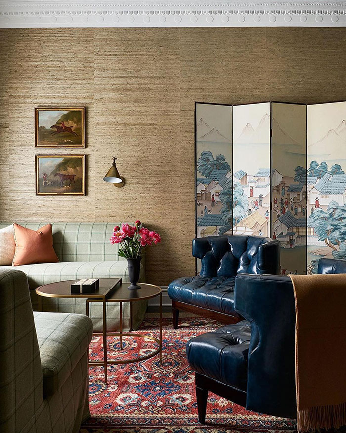 Spacious living room with vintage furniture, leather chairs, patterned rug, and floral accents showcasing home decor ideas.