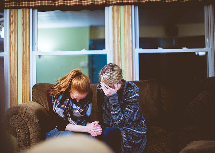 Two women sitting on a couch showing signs of stress and aging, illustrating things that make people look older.