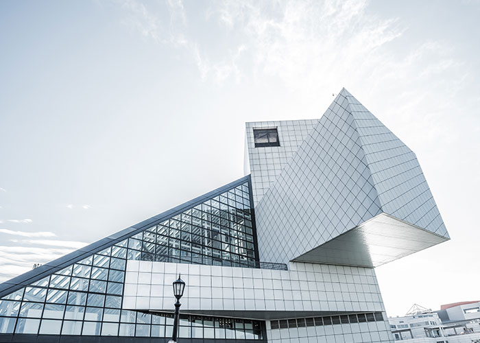 Modern geometric building with glass and metal panels under a bright sky, illustrating factors that make people look older.