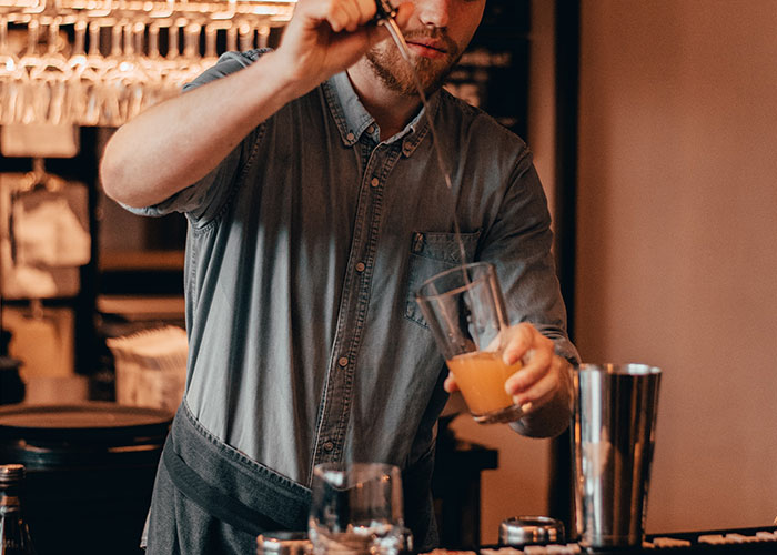 Bartender mixing a drink in a glass at a bar, illustrating lifestyle habits that can make people look older quickly.