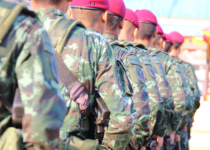 Soldiers in camouflage uniforms and red berets standing in a row, illustrating factors that make people look older.