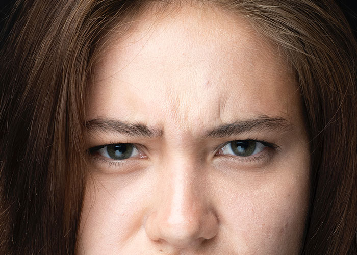 Close-up of a woman showing wrinkles and frown lines, illustrating factors that make people look older fast.
