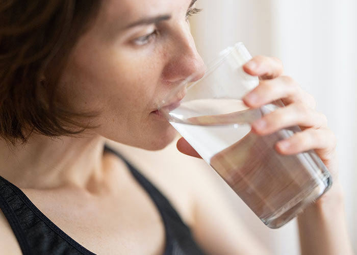 Close-up of a woman drinking water, illustrating common factors that inevitably make people look older over time.