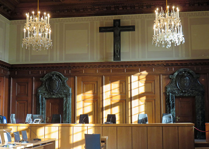 Courtroom interior with wooden paneling, chandeliers, and a crucifix, illustrating factors that make people look older.