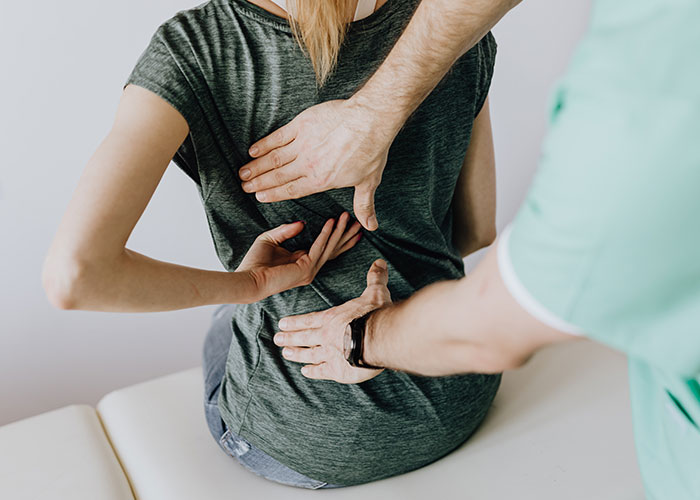 A chiropractor examining a patient's back, illustrating signs that inevitably make people look older.