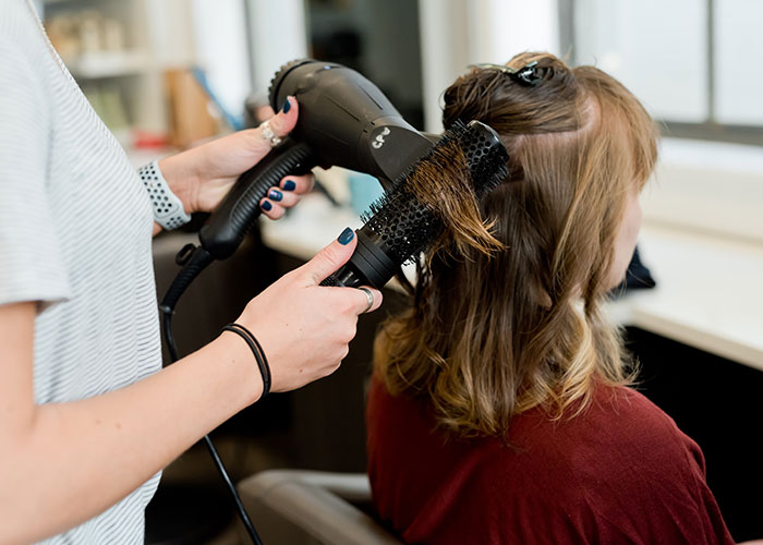 Woman having hair blow-dried in salon, illustrating common things that make people look older.