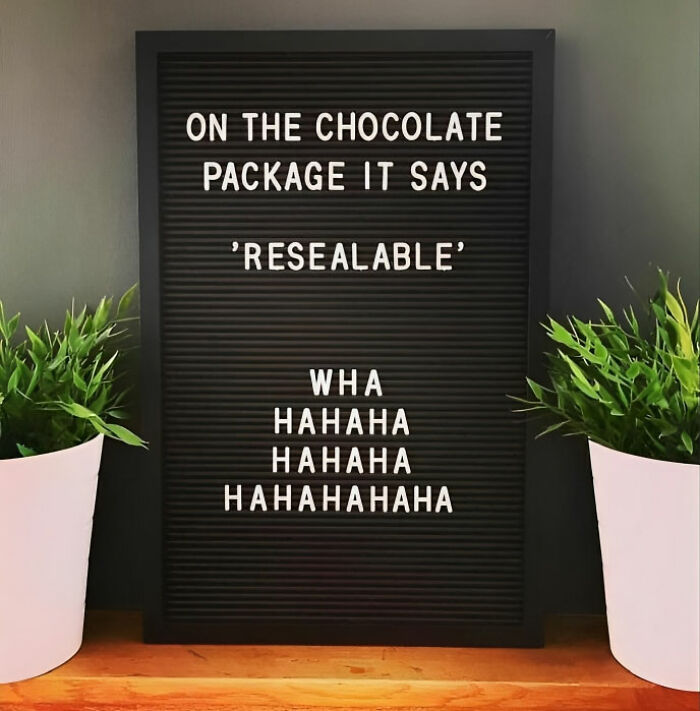 Funny meme on a letter board about resealable chocolate packaging with two potted plants nearby.