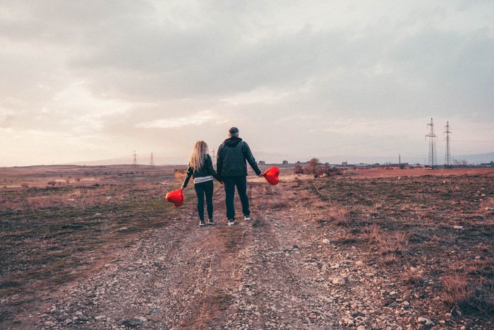 S man and a woman walking down a road with hearth balloons in their hands