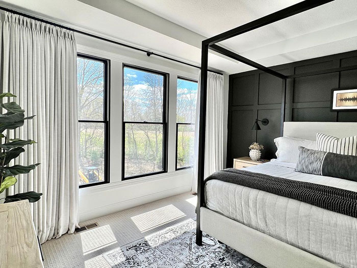 Spacious cozy master bedroom with bright natural light, modern four-poster bed, and black accent wall design ideas.