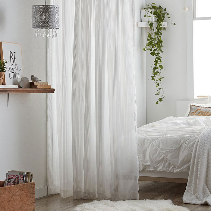 Bright white master bedroom with a sheer curtain room divider creating a cozy and airy design feature.