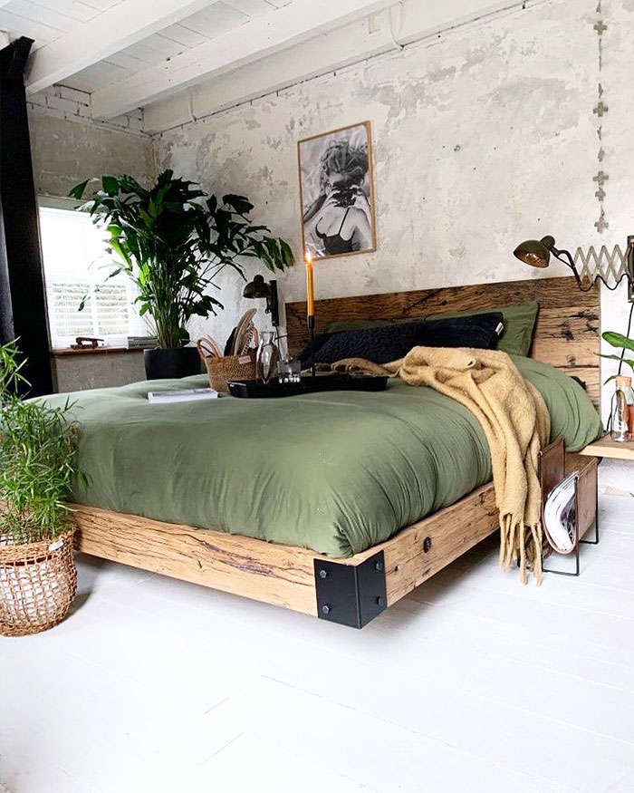 Spacious industrial style master bedroom with green bedding, wooden bed frame, plants, and cozy decor for master bedroom ideas.