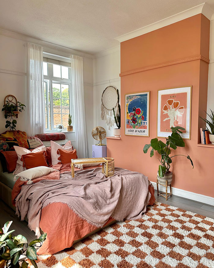 Bohemian style master bedroom ideas with vibrant terracotta walls, layered textiles, plants, and colorful artwork.