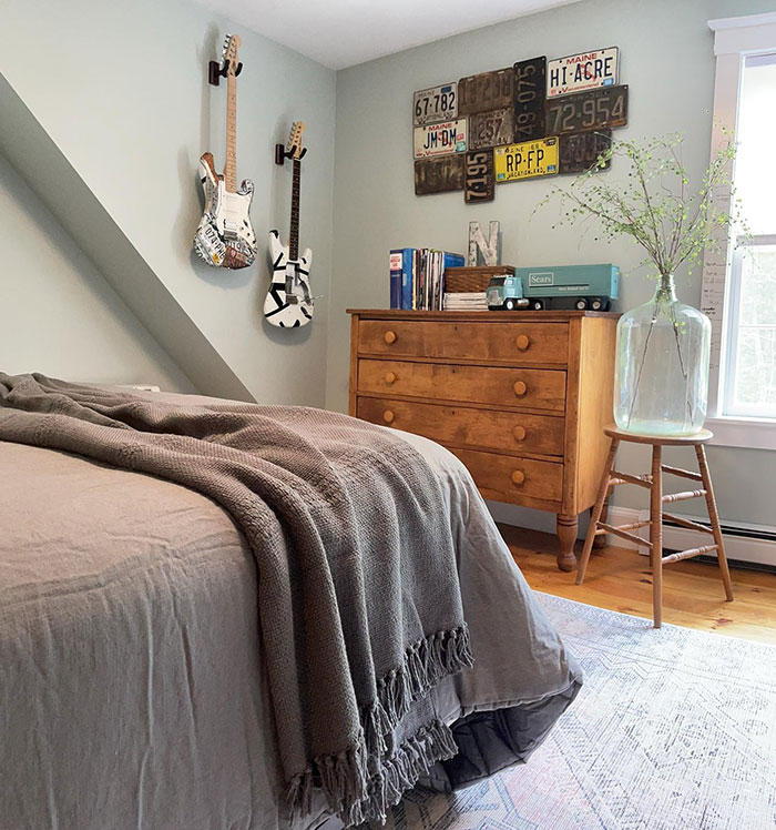 Upcycled materials in cozy master bedroom featuring repurposed guitars, vintage decor, and warm wooden furniture.