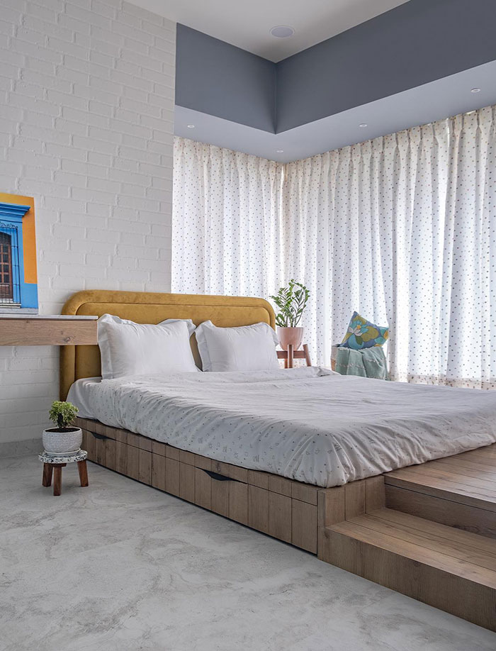 Platform bed in a bright white master bedroom with minimalist design and soft natural light filtering through curtains.