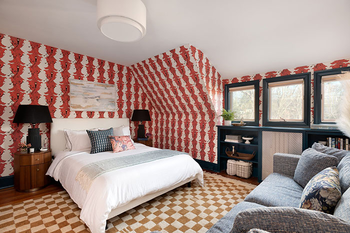 Master bedroom with quirky red patterned wallpaper, white bed, cozy seating, and stylish decor for modern design ideas.