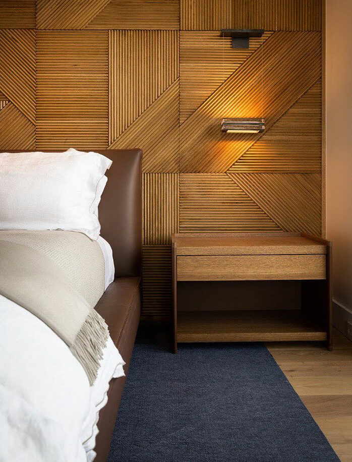 Wood paneling bedroom with modern bedside table and leather bed frame, showcasing stylish master bedroom ideas and design elements.