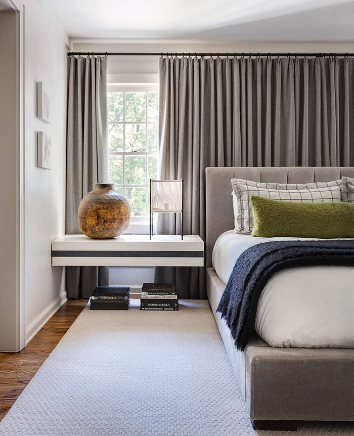 Cozy master bedroom ideas featuring standout grey curtains, a plush bed, and minimalist floating nightstand decor.
