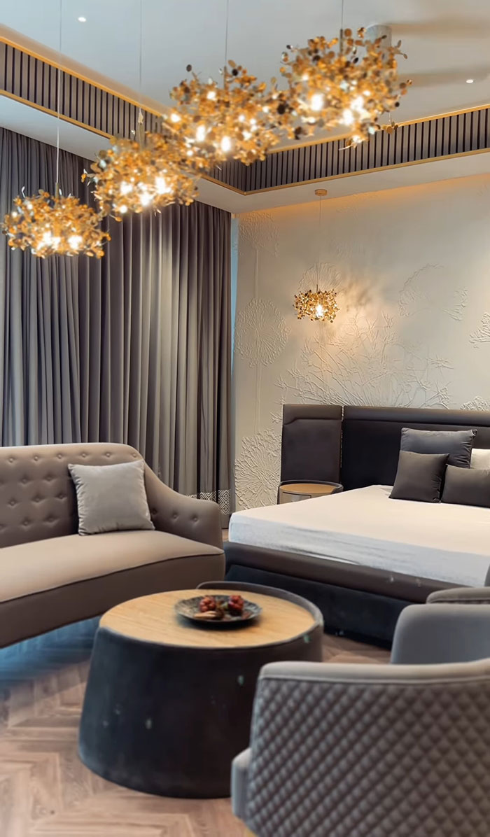 Modern maximalist master bedroom featuring elegant lighting, plush seating, textured wall, and luxurious neutral d&eacute;cor.