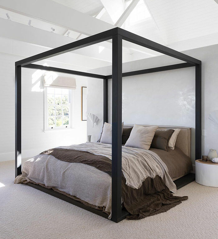 Black canopy bed in a bright white master bedroom showcasing stylish master bedroom ideas and modern design trends.