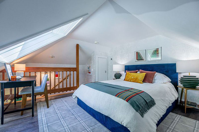 Layered colors in a master bedroom with blue upholstered bed, colorful pillows, and modern decor for elegant design ideas.