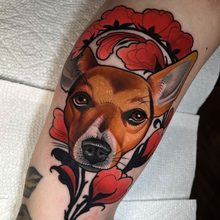 Tattoo of a dog's face framed by red flowers on an arm to honor family.