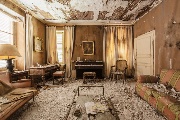 Abandoned room with peeling ceiling and decayed furniture, evoking a post-apocalyptic world in forgotten places.