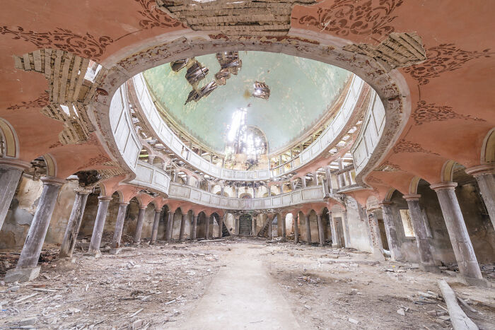 Abandoned post-apocalyptic world scene inside a decaying, ruined building with collapsed ceiling and debris-filled floor.