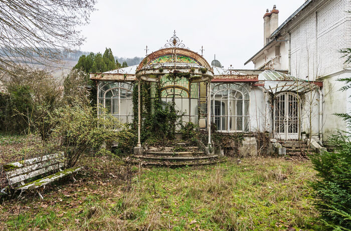 Abandoned place with overgrown vegetation surrounding a deteriorated building in a post-apocalyptic world setting.
