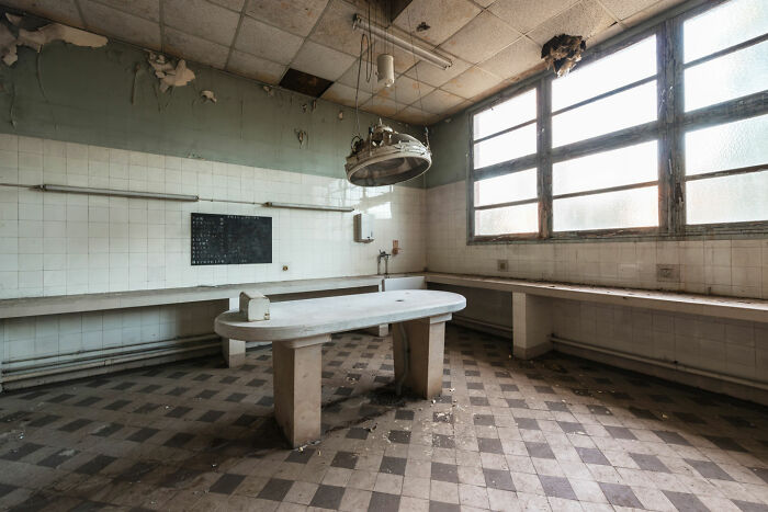 Abandoned room with peeling walls and broken lights in a post-apocalyptic world showing decay and neglect.