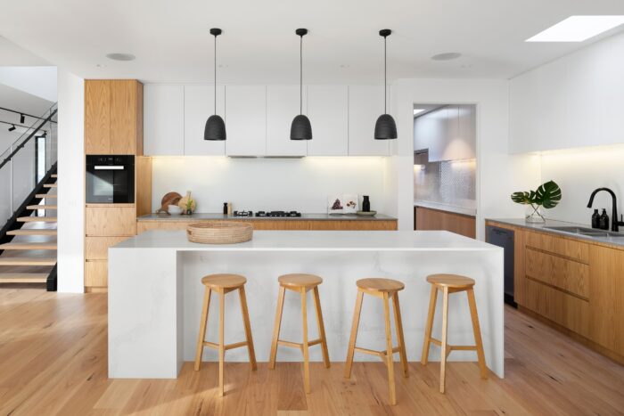 Kitchen with brown wooden seat beside white wooden table and pendant lights Kitchen with brown wooden seat beside white wooden table and pendant lights
