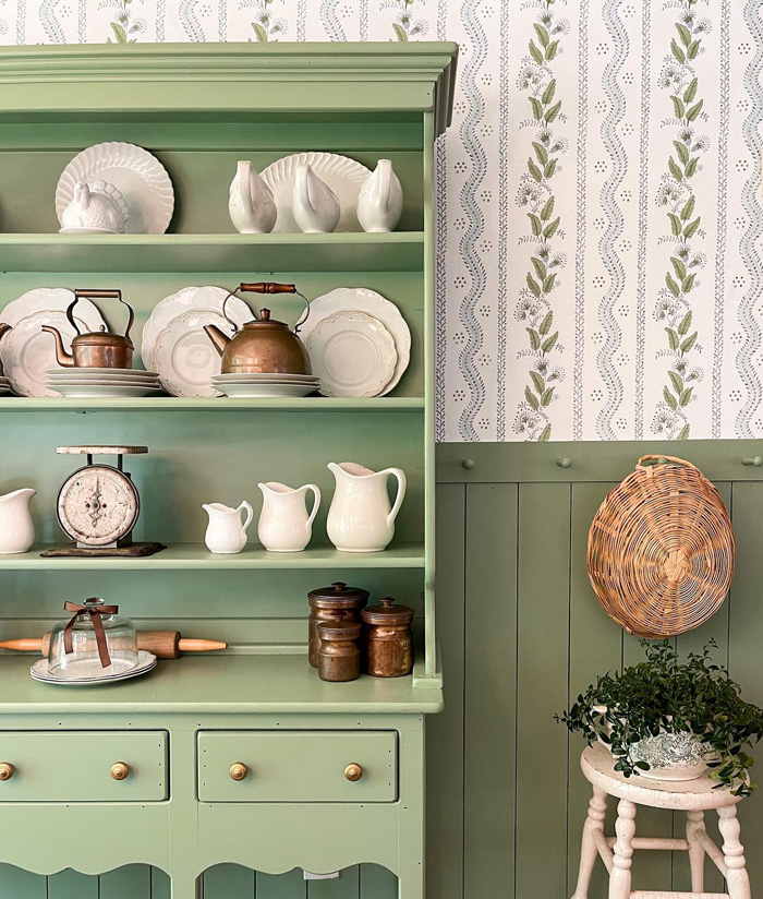 Green sideboards with vintage china and copper kettles against floral removable wallpaper decor ideas background.