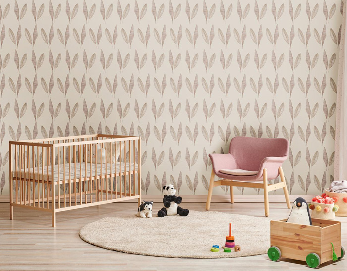 Kids room with feather pattern removable wallpaper, wooden crib, pink chair, toys, and round beige rug.