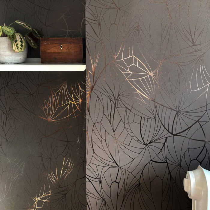 Foil removable wallpaper with metallic leaf patterns on a dark wall, adding stylish decor to transform your space.