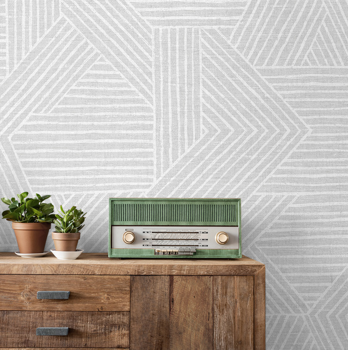 Wallpaper with stylish geometric shapes near a vintage green radio on a wooden surface showcasing removable wallpaper decor ideas.