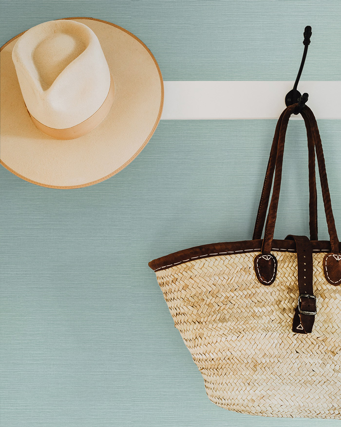 Green removable wallpaper with hat and woven bag hanging on black hooks for stylish wall decor ideas
