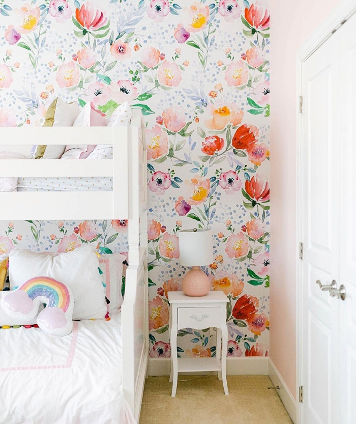 Kid room with floral removable wallpaper decor, white bunk bed, and a small white nightstand with a pink lamp.