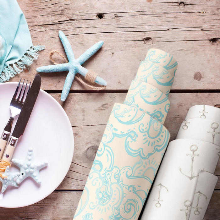 Two rolls of stylish removable wallpaper with blue patterns on a rustic wooden table for decor ideas.