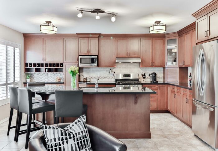 Black leather padded chair beside brown wooden kitchen cabinet and recessed lights Black leather padded chair beside brown wooden kitchen cabinet and recessed lights