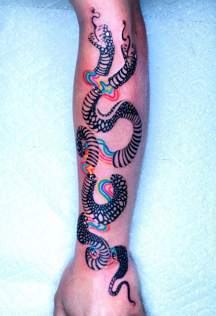 Colorful snake tattoo with abstract patterns on a forearm, showcasing unique body art design.
