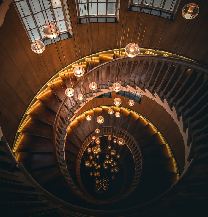wooden spiral staircase with chandeliers