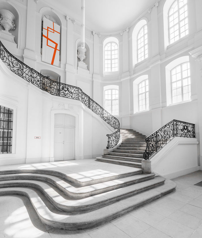 white stairs with black metal railings in a big white concrete building