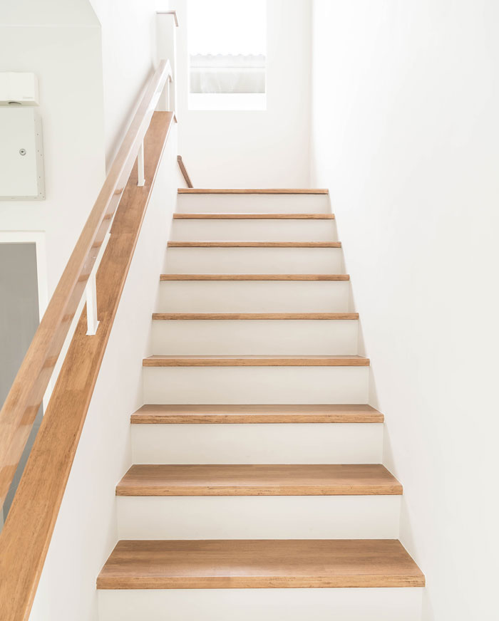straight wooden and white stairs between white walls
